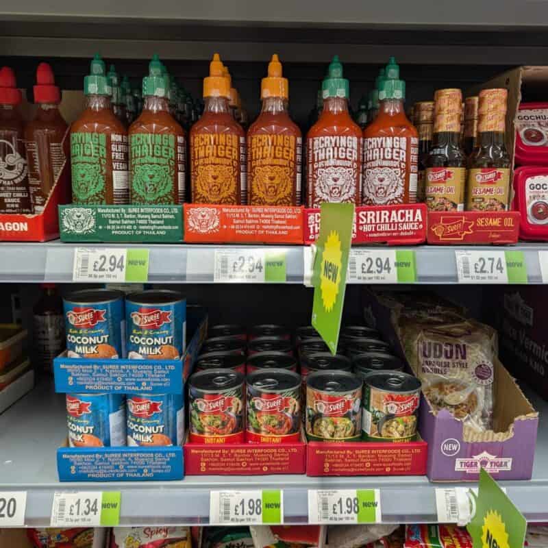 Bottles of Crying Thaiger Sriracha Sauce and Suree brand on the shelves in ASDA, UK