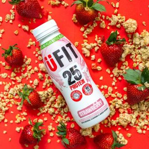 U Fit Strawberry flavour protein drink with strawberries and granola on red background