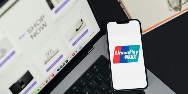 Secure online payment with UnionPay on mobile device, next to a laptop showing an ecommerce store